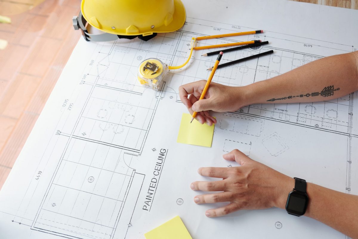 Civil engineer working on construction plan of building and taking notes on stickers